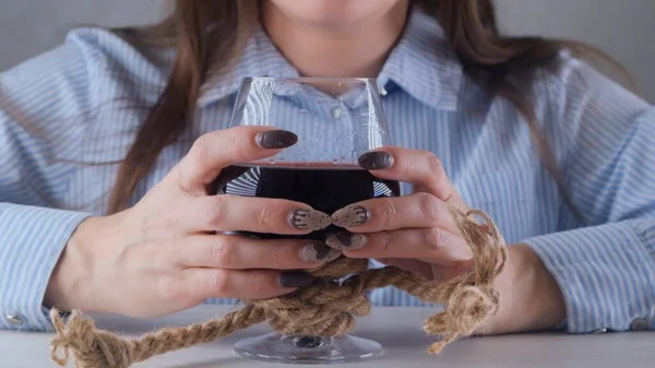 Γυναικεία χέρια που κρατούν ποτήρι κρασιού είναι δεμένα με ένα σχοινί γιούτα. Η έννοια της εξάρτησης από το αλκοόλ. Το πρόβλημα της θεραπείας του αλκοολισμού — Φωτογραφία Αρχείου
