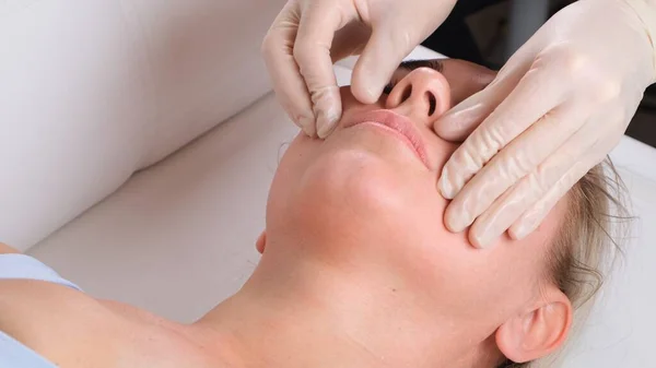 Facial massage beauty treatment. Close up of a young womans face lying on back, getting face lifting massage, pinch and roll technique — Stock Photo, Image