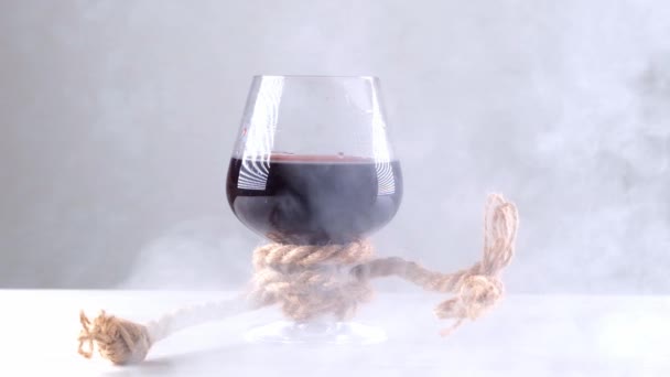 La copa de vino está atada con una cuerda. El concepto de dependencia del alcohol. — Vídeos de Stock