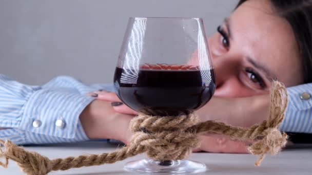 Triste mujer mirando copa de vino atado con cuerda de yute. El concepto de adicción al alcohol. El problema del tratamiento del alcoholismo — Vídeos de Stock