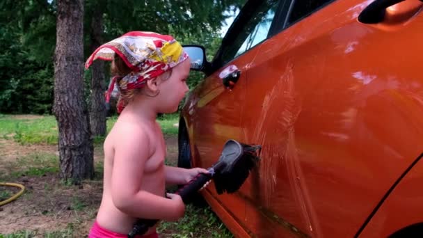 Mixing joke Little girl helps to do Manual car wash with pressurized water in car wash outside in summer. — Stock Video