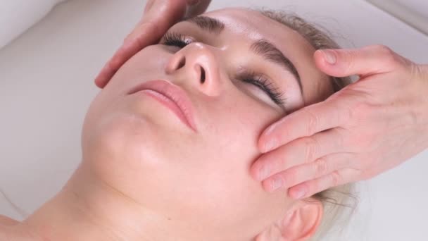 Massaggio viso trattamento di bellezza. Primo piano di una giovane donna faccia sdraiata sulla schiena, ottenere massaggio lifting facciale, pizzicare e rotolare tecnica — Video Stock