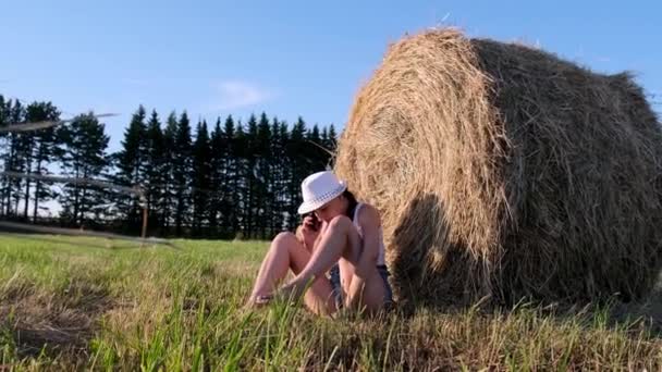 Legrační záběr mladé ženy, jak mluví na smartphonu poblíž kupky sena a mravenci ji kousnou. Ta žena není připravená na venkovský život. Venkovská oblast — Stock video