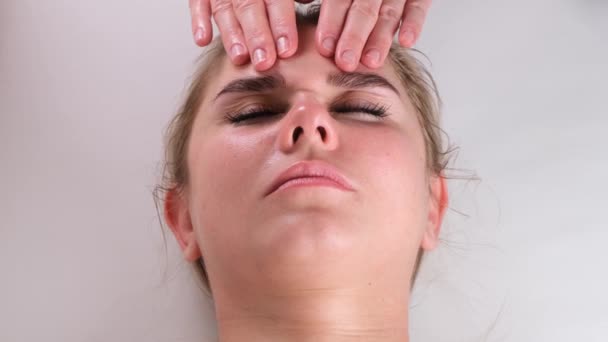 Léčba kosmetické masáže obličeje. Detailní záběr mladé ženy tvář ležící na zádech, dostat masáž obličeje, štípnutí a roll technika — Stock video