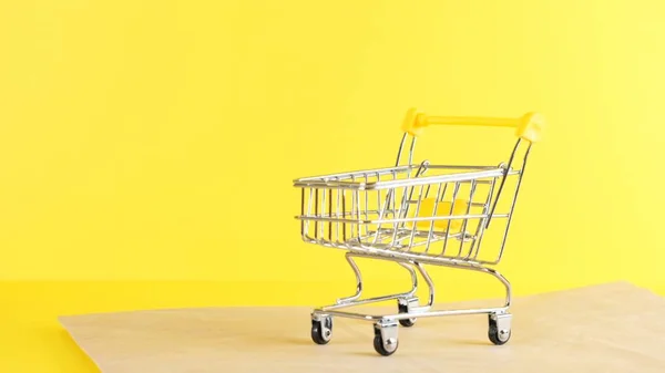 Vacío carrito de compras sobre un fondo amarillo, primer plano. Viernes Negro Compras y descuento Concepto — Foto de Stock