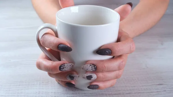 Beautiful manicured nails in the form of chocolate candies on female hands close-up and a cup of coffee. — Stock Photo, Image