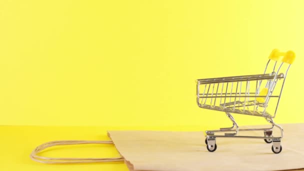Leere Einkaufswagen auf gelbem Hintergrund, Nahaufnahme. Black Friday Shopping und Discount-Konzept — Stockvideo