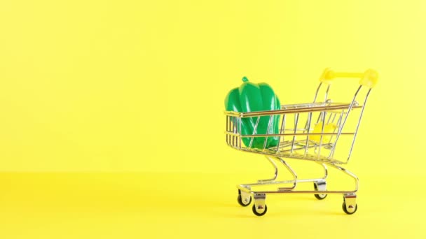 Einkaufswagen mit Gemüse drinnen auf gelbem Hintergrund, Nahaufnahme. Black Friday Shopping und Discount-Konzept. — Stockvideo
