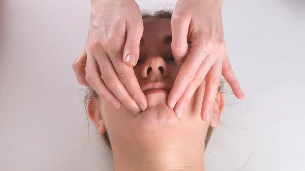 Belle fille a un massage du visage dans une clinique de beauté. concept soin de la peau, concept spa, traitement, massage facial — Photo
