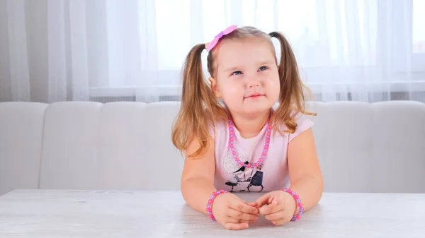 Portrait d'une jolie fille rêveuse mignonne de 3-4 ans avec de grands yeux et une belle coiffure avec un arc rose, enfant riant, perles et autres décorations. — Photo