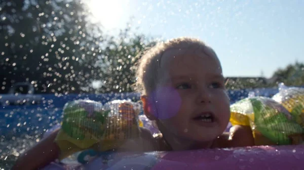 Little girl swims in an inflatable ring in the pool in the backyard: Tyumen, Russia - May 12, 2020. — Stock Photo, Image