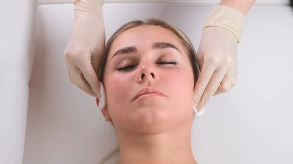 Hermosa chica tiene un masaje facial en una clínica de belleza. Concepto de cuidado facial de la piel . — Foto de Stock