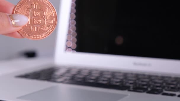 Kadın eli Altın Bitcoin 'i Not Defteri ile tutuyor. Laptop ve Cyrptocurrency Bitcoin Bilgisayar bulanıklığı. para işi dijital konsept. — Stok video