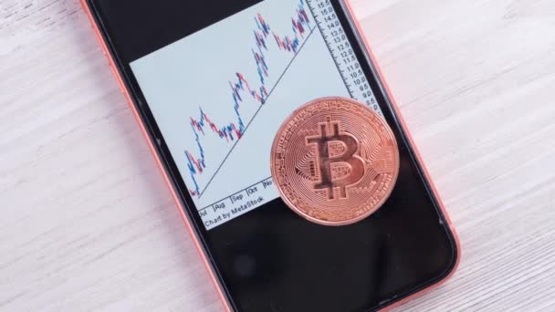 Ekranda Bitcoin ticaret grafiği olan akıllı telefon. Altın Bitcoin Para. Şifreli döviz ticareti: Moskova, Rusya - 31 Mayıs 2021 — Stok video