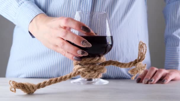 Kvinnlig hand höjer vinglas är bunden med en jute rep. Begreppet alkoholberoende. — Stockvideo
