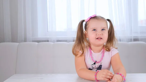 Portrait d'une jolie fille de couvée mignonne de 3-4 ans avec de grands yeux et une belle coiffure avec un arc rose, enfant riant, perles et autres décorations. — Photo