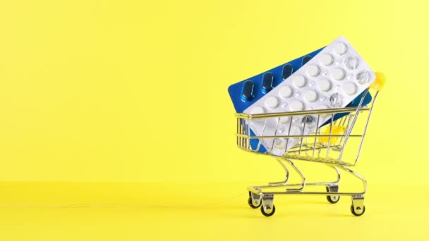 Sarı arka planda hapları olan alışveriş arabası, yakın plan. Tıp konsepti, online alışveriş — Stok video