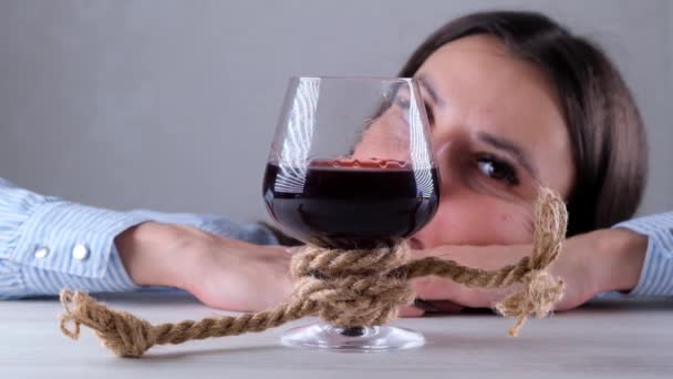 Triste fêmea olhando copo de vinho amarrado com corda de juta. O conceito de dependência de álcool. O problema do tratamento do alcoolismo — Vídeo de Stock