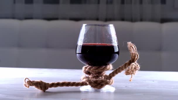 El vino se vierte en vidrio se ata con una cuerda. El concepto de dependencia del alcohol. — Vídeo de stock