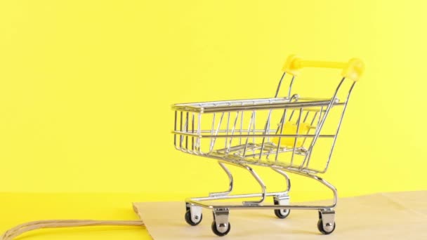 Leeg Winkelwagen op een gele achtergrond, close-up. Black Friday Shopping en Korting Concept — Stockvideo