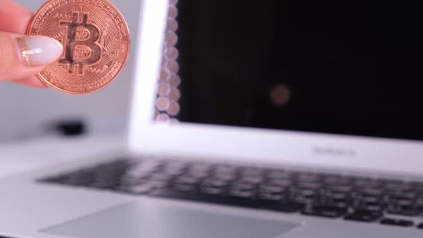 Mano femminile tiene bitcoin d'oro con notebook. Sfocatura di un computer portatile e Cyrptocurrency Bitcoin Computer. business of money concetto digitale. — Video Stock