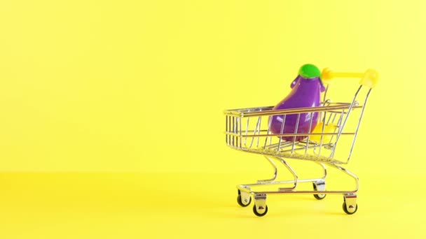 Winkelwagen met groenten binnen op een gele achtergrond, close-up. Black Friday Shopping en Korting Concept. — Stockvideo