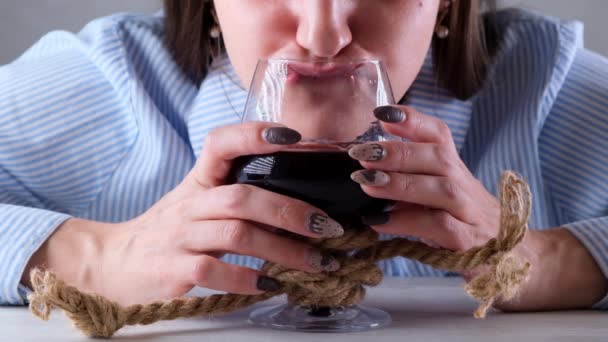 Bebidas divertidas femeninas de una copa de vino atada con una cuerda de yute. El concepto de adicción al alcohol. El problema del tratamiento del alcoholismo — Vídeos de Stock