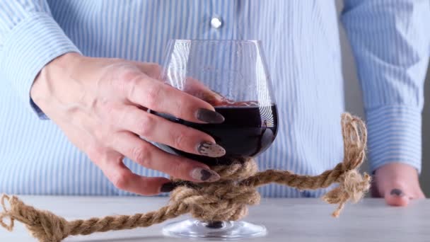 Mano femenina sosteniendo copa de vino está atado con una cuerda de yute. El concepto de dependencia del alcohol. — Vídeo de stock