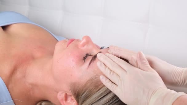Bella ragazza ha un massaggio facciale in una clinica di bellezza. concetto cura della pelle, concetto di spa, trattamento, massaggio facciale — Video Stock