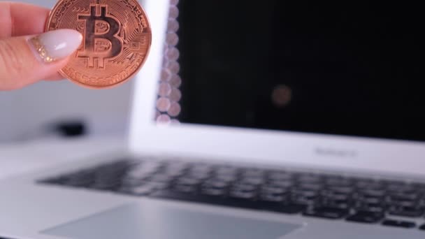 Vrouwelijke hand houdt Golden bitcoin met Notebook. Wazig van een laptop en Cyrptocurrency Bitcoin Computer. business of money digitaal concept. — Stockvideo