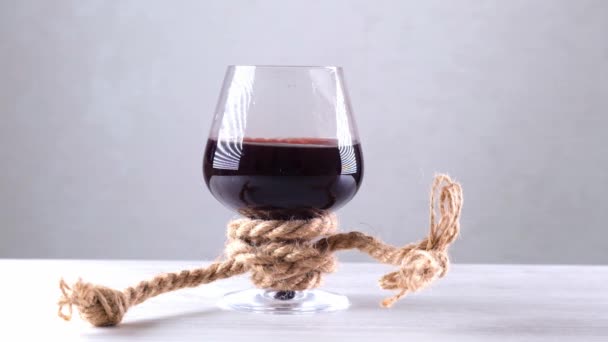 Sklenice na víno je přivázaná provazem. Koncept závislosti na alkoholu. — Stock video