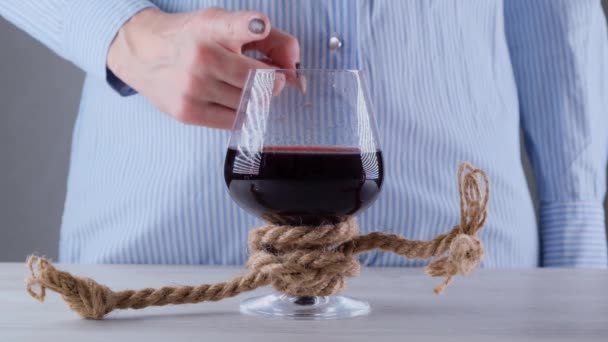 女性的手显示出不能的迹象，停止在酒杯上，用黄麻绳捆绑。酒精成瘾的概念。酗酒治疗的问题 — 图库视频影像