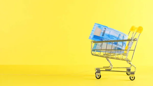 Carro de compras con billete de 2000 rublos sobre fondo amarillo, primer plano. Viernes Negro Compras y descuento Concepto — Foto de Stock