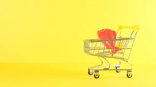 黄色の背景に魚とショッピングカート、閉じます。ブラックフライデーショッピング&割引コンセプト. — ストック写真