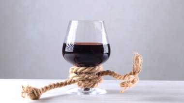 Şarap kadehi bir iple bağlanmış. Alkol bağımlılığı kavramı.
