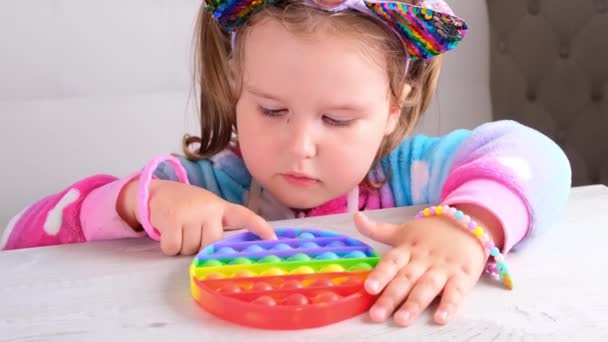 Cute little girls with pop it sensory toy circle form. little female presses colorful rainbow squishy soft silicone bubbles on white background. Stress and anxiety relief. Trendy fidgeting game. — Stock Video