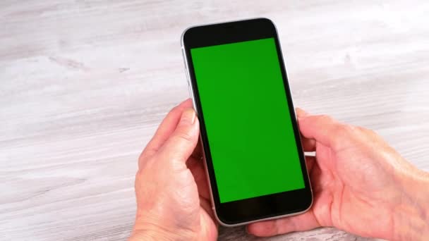 Hands Middle-aged female senora uses an iPhone smartphone with a chroma key screen, copy space. Online shopping concept, use of mobile applications: Moscow, Russia - June 24, 2021. — Stock Video