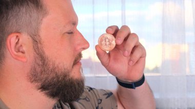 Elinde altın bir bitcoin tutan bir adamın portresi. Madencilik, kripto para birimi, madencilik ve elektronik parayla yerleşim.