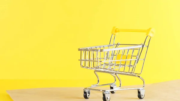 Leere Einkaufswagen auf gelbem Hintergrund, Nahaufnahme. Black Friday Shopping und Discount-Konzept — Stockfoto