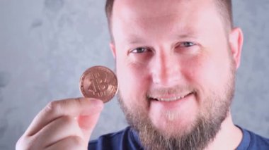 Elinde altın bir bitcoin tutan sakallı zengin bir adamın portresi. Madencilik, kripto para birimi, madencilik ve elektronik parayla yerleşim.