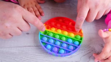 Şirin küçük kızlar babalarıyla oynuyorlar. Duyusal oyuncak çemberi formunda. Küçük dişi, beyaz arka planda renkli gökkuşağı yumuşak silikon kabarcıklar oluşturur. Stres ve endişe giderici. Eğilim