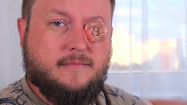 Homme détient Bitcoins. Homme avec Bitcoin dans les yeux. Bitcoin est une crypto-monnaie inventée en 2008 par une personne inconnue ou un groupe de personnes utilisant le nom Satoshi Nakamoto. — Video