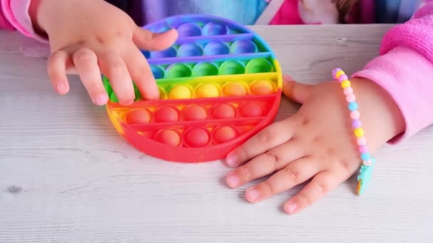 赤ちゃんの女性の手は、ポップそれ感覚おもちゃ円の形で遊んでいる。小さな女性は白い背景にカラフルな虹色のずさんな柔らかいシリコーン泡を押す。ストレスと不安緩和。トレンディ・フィディング — ストック動画