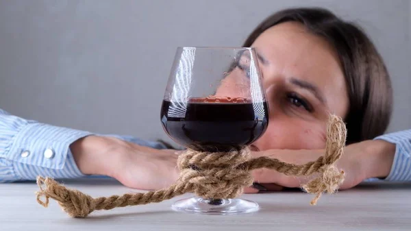 Triste fêmea olhando copo de vinho amarrado com corda de juta. O conceito de dependência de álcool. O problema do tratamento do alcoolismo — Fotografia de Stock