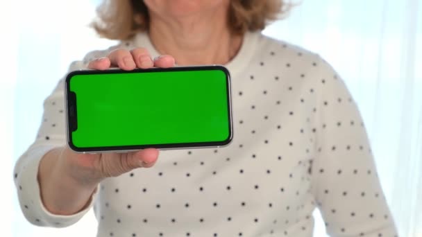 Μεσήλικες γυναίκες σενιόρα χρησιμοποιεί ένα iPhone smartphone με μια οθόνη κλειδί chroma, αντίγραφο χώρο, κοντά. Online εμπορική ιδέα, χρήση εφαρμογών για κινητά: Μόσχα, Ρωσία - 24 Ιουνίου 2021. — Αρχείο Βίντεο