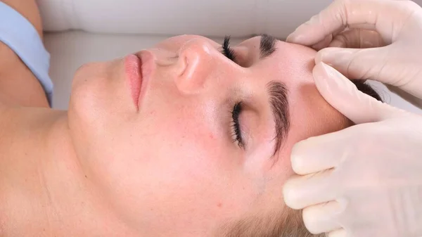 Menina bonita tem uma massagem facial em uma clínica de beleza. conceito cuidados com a pele, conceito de spa, tratamento, massagem facial — Fotografia de Stock