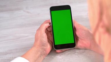 Orta yaşlı kadınlardan yeni normal konseptte ulaşılamıyor ve yeşil ekranlı akıllı telefon kullanılıyor: Moskova, Rusya - 24 Haziran 2021.