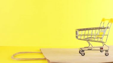 Sarı arka planda boş bir alışveriş arabası, yakın plan. Kara Cuma Alışveriş ve İndirim Konsepti