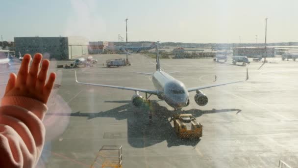 Bambina che guarda l'aereo parcheggiato all'aeroporto di Mosca attraverso la finestra del cancello. Manutenzione e preparazione dell'aeromobile per il reggimento. Vacanza, viaggi, aspettative e sogni concetto. — Video Stock