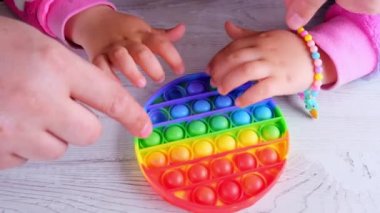 Şirin küçük kızlar babalarıyla oynuyorlar. Duyusal oyuncak çemberi formunda. Küçük dişi, beyaz arka planda renkli gökkuşağı yumuşak silikon kabarcıklar oluşturur. Stres ve endişe giderici. Eğilim